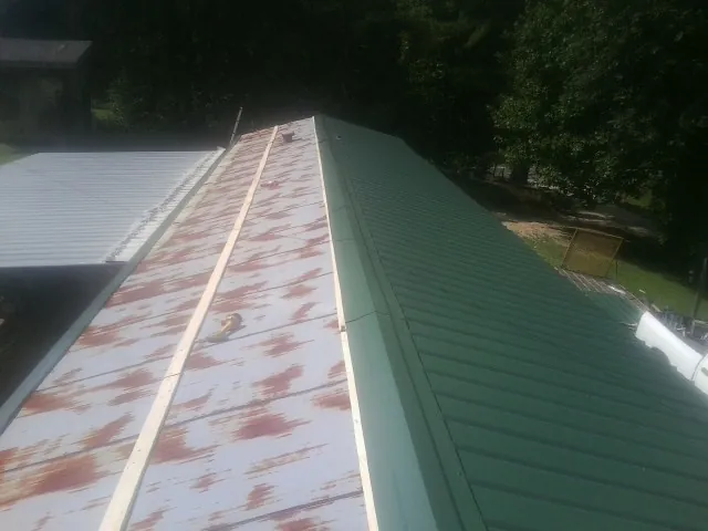 Old rusted panels beside newly installed green metal roofing — Wind Damage Roof Repair by Roofing Brothers in Ashland