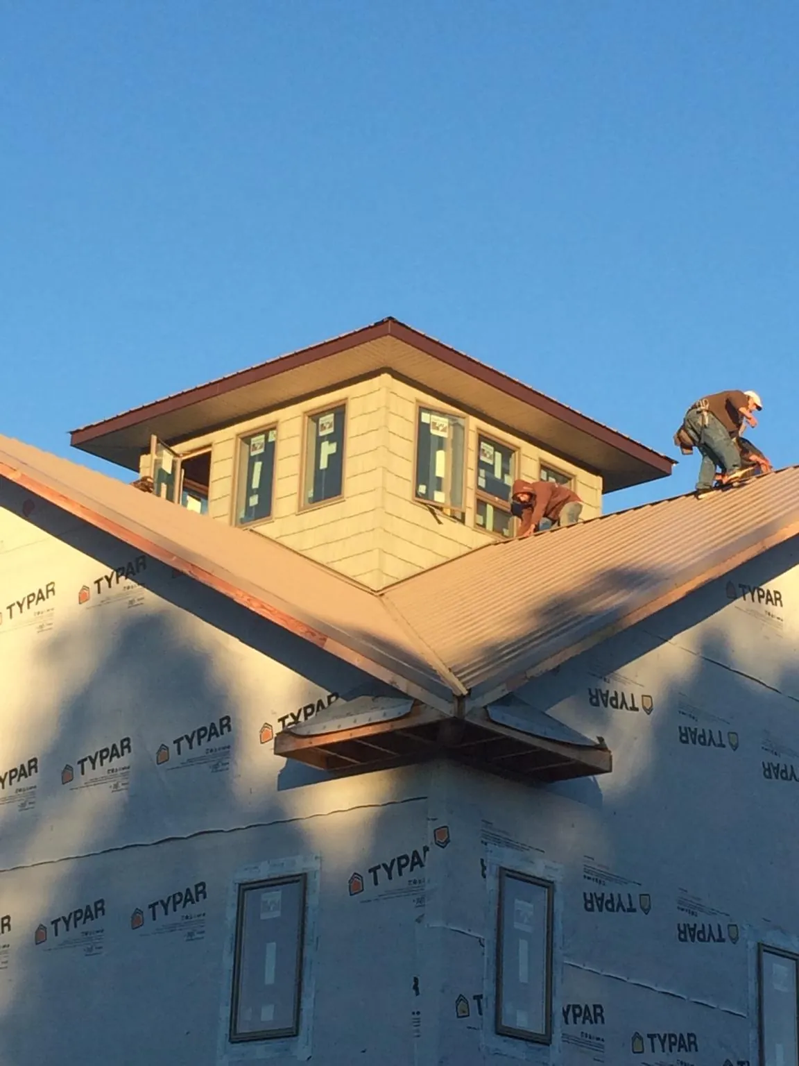 Roofers working around a rooftop cupola on a new metal roof at sunset — Roof Waterproofing in Ashland by Roofing Brothers